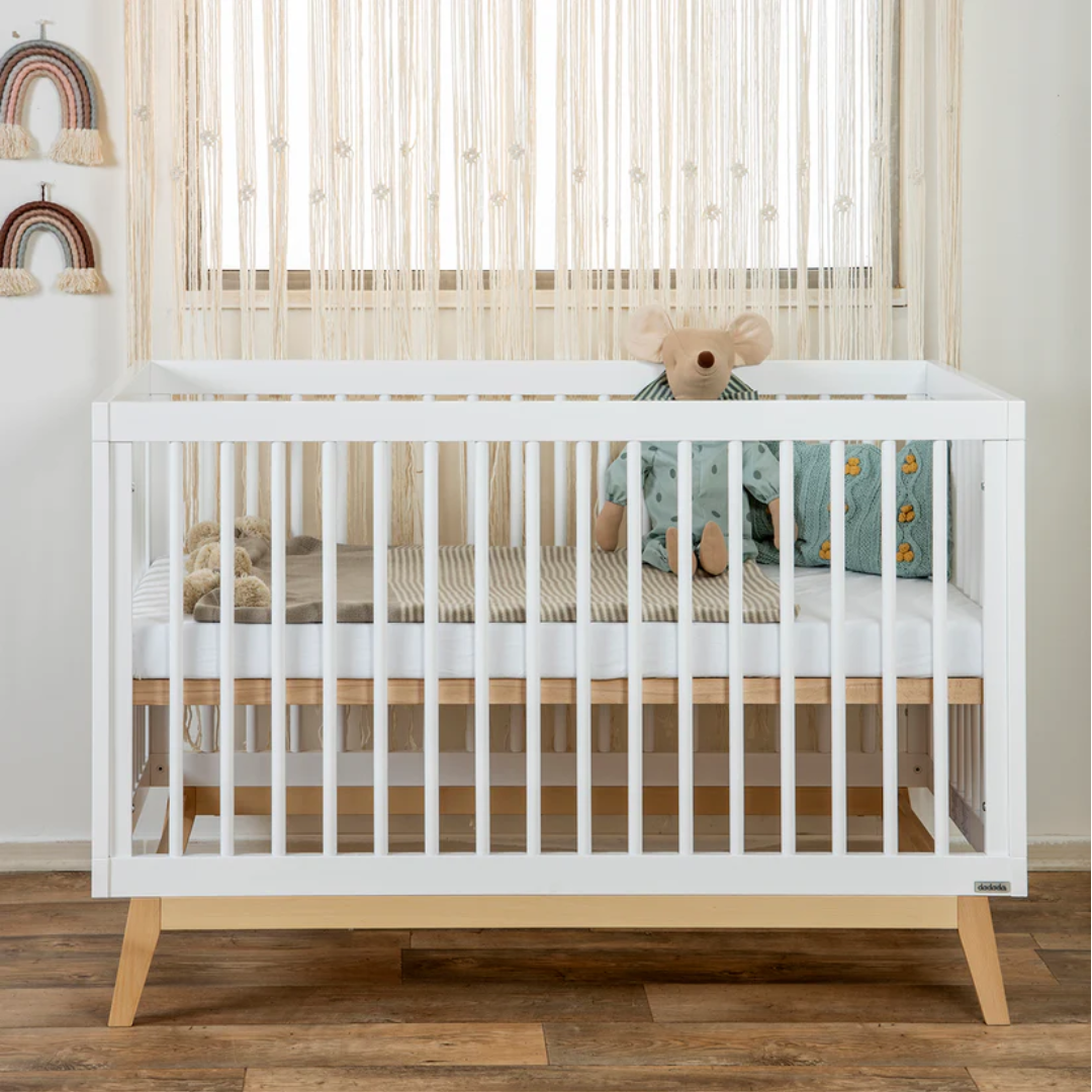 a white crib with a stuffed animal in it